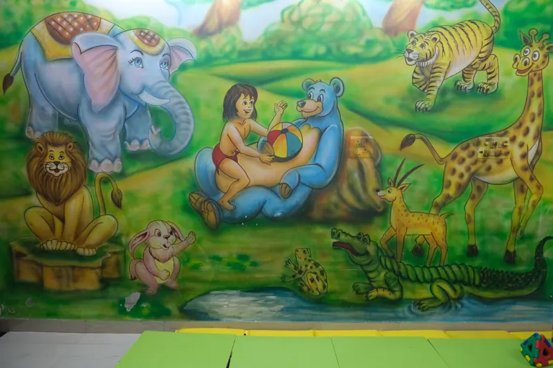 A hand-painted jungle mural with elephants, lions and a bear on a classroom wall